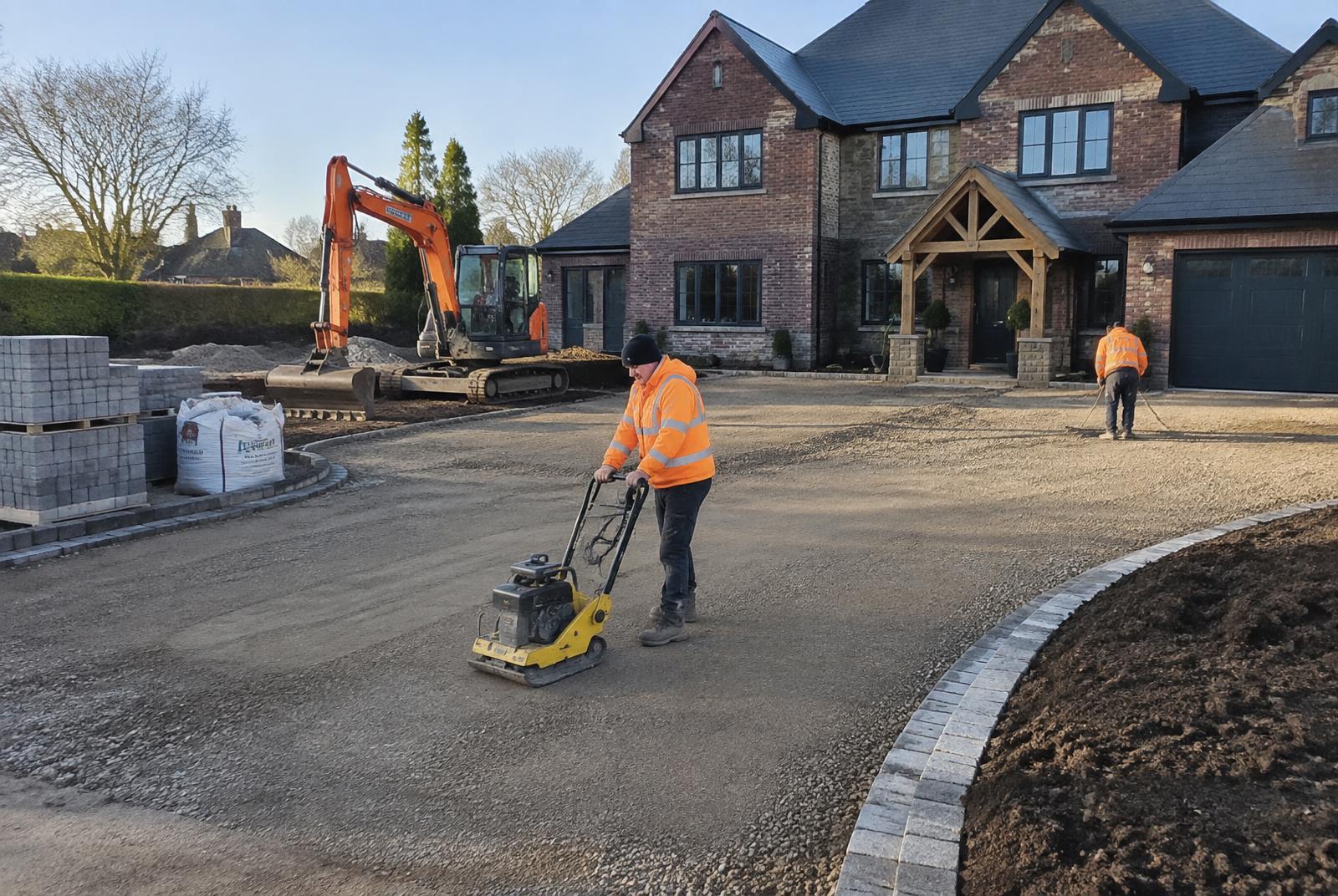 Groundworks team compacting a sub base for a large driveway at a detached house
